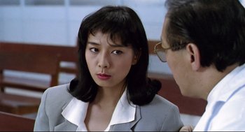 Movie still from “Hard Boiled” (1992), directed by John Woo – An asian woman in a business suit talking to an older man; Close Up shot, Over the shoulder angle