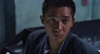 Movie still from “Hard Boiled” (1992), directed by John Woo – A person sitting in a chair looking at the camera; Close Up shot, High angle