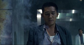 Movie still from “Hard Boiled” (1992), directed by John Woo – A man in a suit and tie smoking a cigarette; Medium shot, Low angle