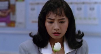 Movie still from “Hard Boiled” (1992), directed by John Woo – A woman holding a white flower in her hand; Close Up shot, High angle