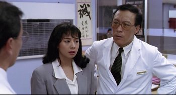 Movie still from “Hard Boiled” (1992), directed by John Woo – An asian man and a woman standing next to each other; Medium shot, Low angle