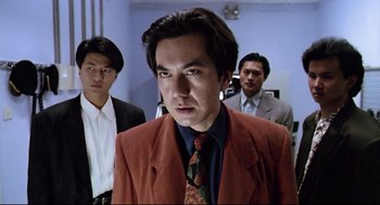 Movie still from “Hard Boiled” (1992), directed by John Woo – A man in a red jacket and a red tie; Medium shot, Low angle