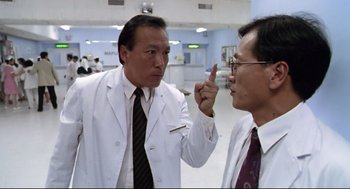 Movie still from “Hard Boiled” (1992), directed by John Woo – Two men in white lab coats talking to each other; Medium shot, Low angle