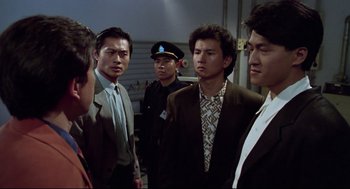 Movie still from “Hard Boiled” (1992), directed by John Woo – A group of men standing next to each other in a room; Medium shot, Over the shoulder angle