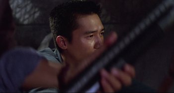 Movie still from “Hard Boiled” (1992), directed by John Woo – A young man holding a guitar in his hands; Close Up shot, Low angle