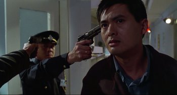 Movie still from “Hard Boiled” (1992), directed by John Woo – A man holding a gun up to his head; Close Up shot, Low angle