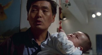 Movie still from “Hard Boiled” (1992), directed by John Woo – A man holding a baby in his arms and crying; Close Up shot, Low angle