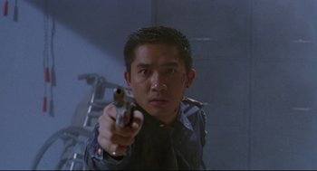 Movie still from “Hard Boiled” (1992), directed by John Woo – A man is holding a gun in a room; Close Up shot, Low angle