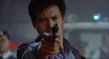 Movie still from “Hard Boiled” (1992), directed by John Woo – A man holding a gun in his right hand; Close Up shot, Low angle