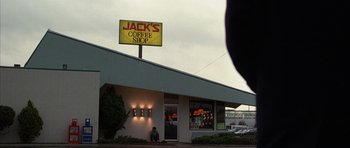 Movie still from “Hard Eight” (1996), directed by Paul Thomas Anderson – A man sitting on the sidewalk outside of a coffee shop; Wide shot, Low angle