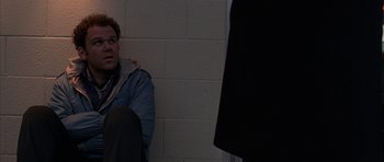 Movie still from “Hard Eight” (1996), directed by Paul Thomas Anderson – A man sitting on the ground next to a brick wall; Medium shot, High angle