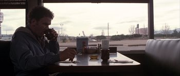 Movie still from “Hard Eight” (1996), directed by Paul Thomas Anderson – A person sitting at a table with a cup of coffee; Medium shot, Over the shoulder angle
