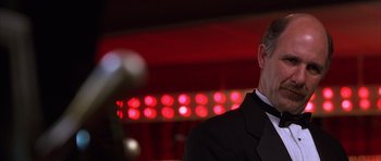 Movie still from “Hard Eight” (1996), directed by Paul Thomas Anderson – A man wearing a suit and tie in front of red lights; Close Up shot, Low angle