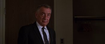 Movie still from “Hard Eight” (1996), directed by Paul Thomas Anderson – A man in a suit and tie standing in front of a wall; Close Up shot, Over the shoulder angle