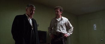 Movie still from “Hard Eight” (1996), directed by Paul Thomas Anderson – Two men standing next to each other in a living room; Medium shot, Low angle