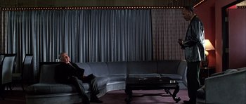 Movie still from “Hard Eight” (1996), directed by Paul Thomas Anderson – A man sitting on a couch next to a coffee table in a room; Wide shot, High angle