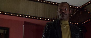 Movie still from “Hard Eight” (1996), directed by Paul Thomas Anderson – A man wearing a black jacket and a yellow shirt; Close Up shot, Low angle