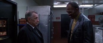 Movie still from “Hard Eight” (1996), directed by Paul Thomas Anderson – Two men in suits are standing next to each other in a kitchen; Medium shot, Low angle