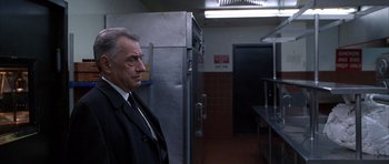 Movie still from “Hard Eight” (1996), directed by Paul Thomas Anderson – A man in a suit and tie standing in front of a refrigerator in a kitchen; Medium shot, Low angle