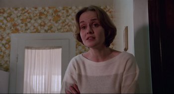 Movie still from “Hardcore” (1979), directed by Paul Schrader – A woman standing in front of a door looking sad; Medium shot, Low angle