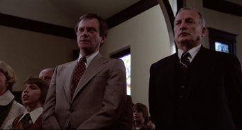 Movie still from “Hardcore” (1979), directed by Paul Schrader – A man in a suit and tie standing next to another man in a suit and tie; Medium shot, Low angle