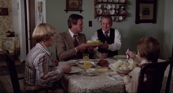 Movie still from “Hardcore” (1979), directed by Paul Schrader – A group of people sitting around a table with plates of food; Medium shot, High angle