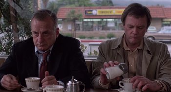 Movie still from “Hardcore” (1979), directed by Paul Schrader – Two men sitting at a table in front of a coffee pot; Medium shot, Low angle