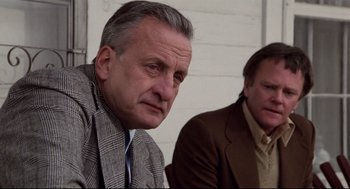 Movie still from “Hardcore” (1979), directed by Paul Schrader – Two men sitting next to each other in front of a white wall; Close Up shot, Low angle