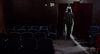 Movie still from “Hardcore” (1979), directed by Paul Schrader – A man walking into a room with rows of blue chairs; Wide shot, High angle