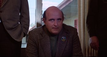 Movie still from “Hardcore” (1979), directed by Paul Schrader – A man with a bald head wearing a green shirt; Close Up shot, Over the shoulder angle