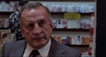 Movie still from “Hardcore” (1979), directed by Paul Schrader – An older man wearing a suit and tie in front of shelves of books; Close Up shot, Low angle