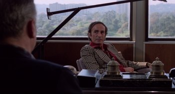 Movie still from “Hardcore” (1979), directed by Paul Schrader – A man sitting at a table in front of a window; Medium shot, Over the shoulder angle