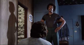 Movie still from “Hardcore” (1979), directed by Paul Schrader – A man standing in front of a mirror in front of a woman; Medium shot, Low angle