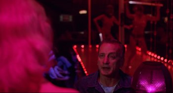 Movie still from “Hardcore” (1979), directed by Paul Schrader – A man in a purple shirt is in a room with red lights; Close Up shot, Over the shoulder angle