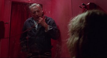 Movie still from “Hardcore” (1979), directed by Paul Schrader – A man talking on a phone in front of a mirror; Medium shot, Over the shoulder angle
