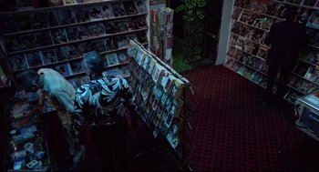 Movie still from “Hardcore” (1979), directed by Paul Schrader – A man sitting in front of a rack of cards; Wide shot, Overhead angle