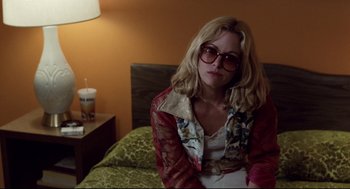 Movie still from “Hardcore” (1979), directed by Paul Schrader – A woman sitting on top of a bed in a room; Medium shot, Over the shoulder angle