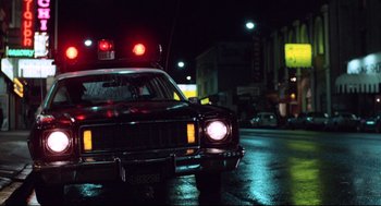 Movie still from “Hardcore” (1979), directed by Paul Schrader – A police car with its lights turned on at night; Wide shot, Low angle