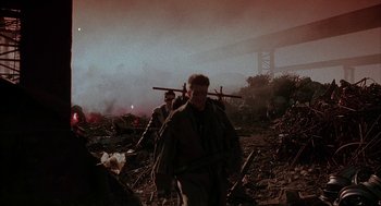 Movie still from “Hardware” (1990), directed by Richard Stanley – A group of people walking through a field; Wide shot, Low angle