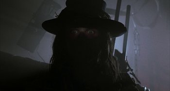 Movie still from “Hardware” (1990), directed by Richard Stanley – A person with a hat and a long black hair; Close Up shot, Low angle