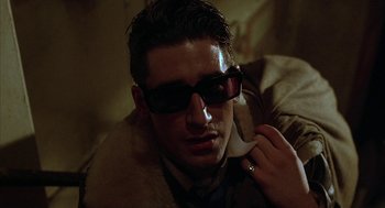 Movie still from “Hardware” (1990), directed by Richard Stanley – A man wearing sunglasses while talking on a cell phone; Close Up shot, Low angle