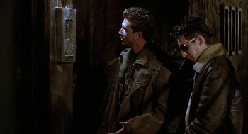 Movie still from “Hardware” (1990), directed by Richard Stanley – Two men are standing next to each other; Medium shot, Low angle