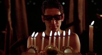 Movie still from “Hardware” (1990), directed by Richard Stanley – A man in sunglasses looking at candles on top of a cake; Close Up shot, Low angle