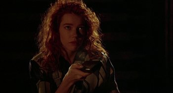 Movie still from “Hardware” (1990), directed by Richard Stanley – A woman with red hair holding a cell phone; Close Up shot, Low angle