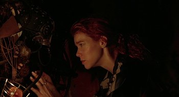 Movie still from “Hardware” (1990), directed by Richard Stanley – A woman with red hair looking into a mirror; Close Up shot, Low angle
