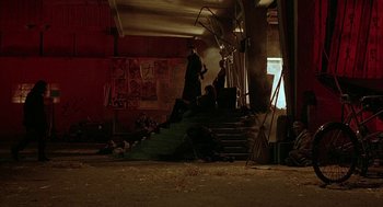 Movie still from “Hardware” (1990), directed by Richard Stanley – A group of people sitting on top of a set of stairs; Wide shot, High angle
