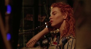 Movie still from “Hardware” (1990), directed by Richard Stanley – A woman with red curly hair holding a phone to her ear; Close Up shot, Low angle