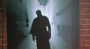 Movie still from “Hardware” (1990), directed by Richard Stanley – A man is walking down a dark hallway; Wide shot, Low angle