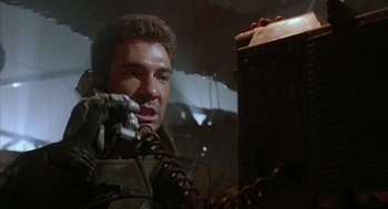 Movie still from “Hardware” (1990), directed by Richard Stanley – A man holding a gun while standing next to a mirror; Close Up shot, Low angle