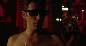 Movie still from “Hardware” (1990), directed by Richard Stanley – A man wearing sunglasses and a gold necklace; Close Up shot, Low angle